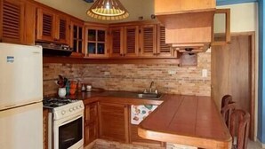 Una cocina con armarios de madera, estufa y lámpara colgante.