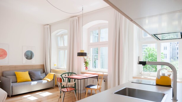 Una cocina moderna con un lavamanos, una mesa de comedor y un sofá.