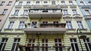 Un edificio de varios pisos con un balcón central, múltiples ventanas y un farol.
