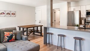 Een moderne keuken met een roestvrijstalen koelkast, een houten eettafel en een bar met krukken.