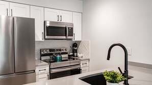 Een moderne keuken met roestvrijstalen apparatuur, witte kasten en een zwarte spoelbak.