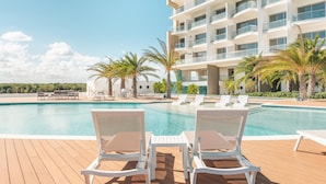 A modern hotel with a pool area featuring white lounge chairs and palm trees. - 7 Mares D12 in Punta Cana (Punta Cana)