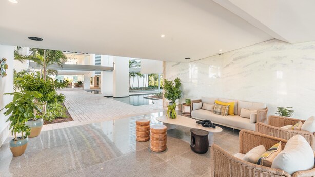 A spacious lobby with a modern design, featuring a seating area with wicker furniture and a marble wall. - 7 Mares D12 in Punta Cana (Punta Cana)