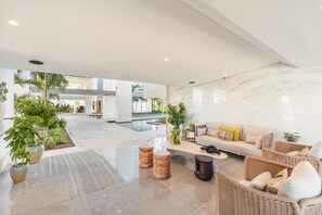 A spacious lobby with a modern design, featuring a seating area with wicker furniture and a marble wall. - 7 Mares D12 in Punta Cana (Punta Cana)