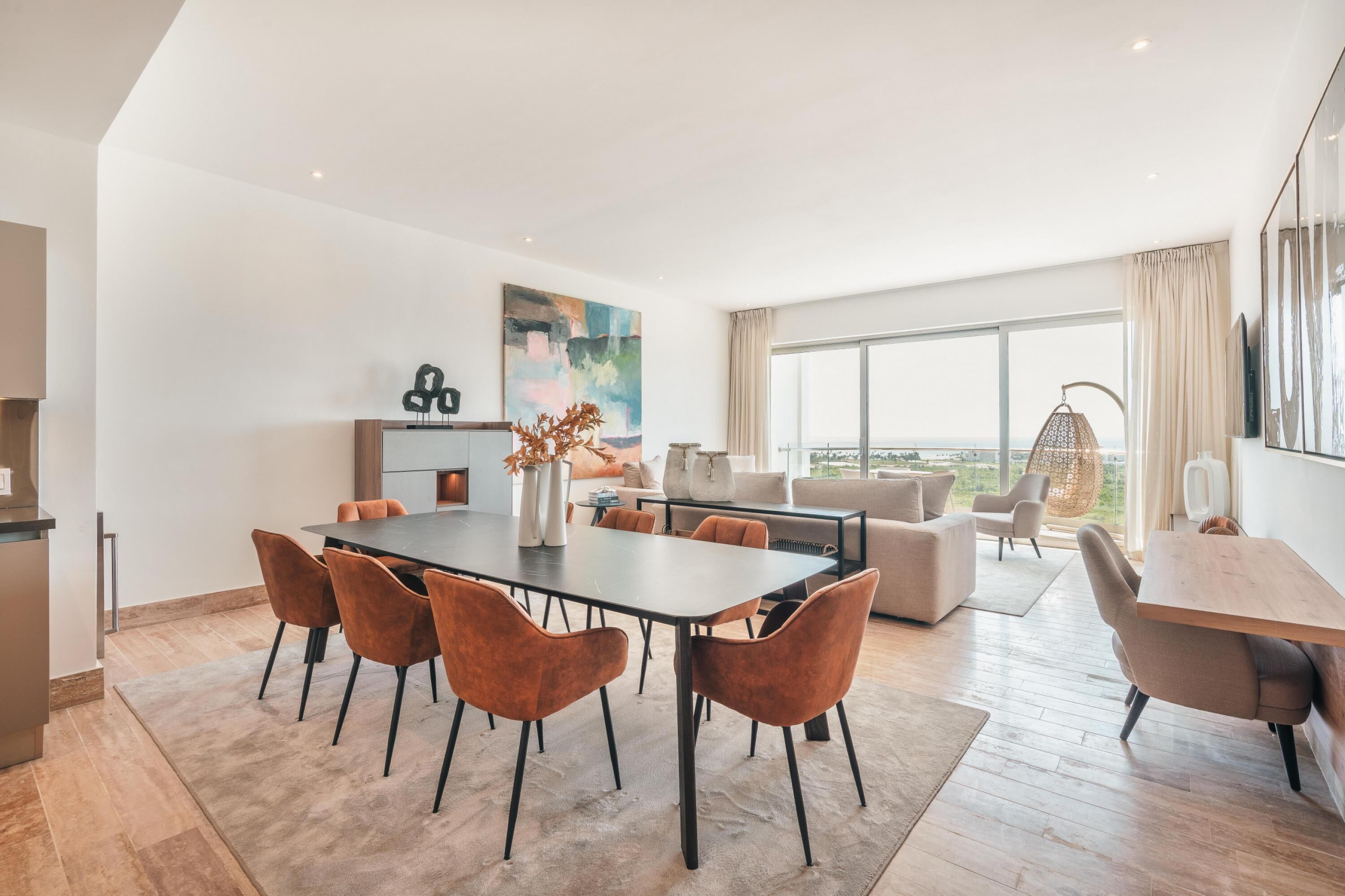A modern living room with a dining area, large windows, and a view of the outdoors.