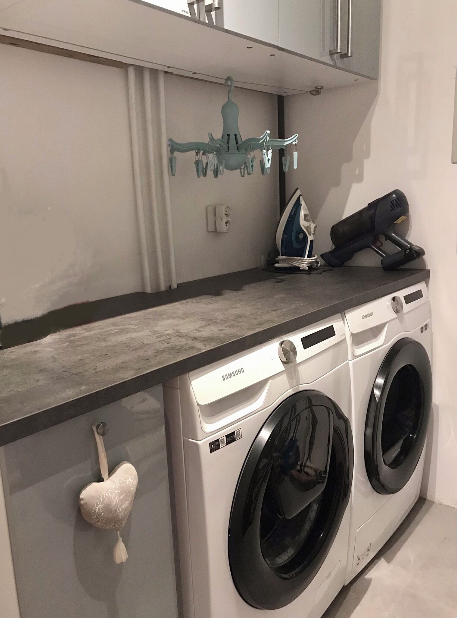 A laundry area with a washing machine and dryer, a towel rack, and a wall-mounted ironing board.