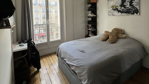 A bedroom with a bed, a desk, and a window.