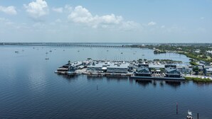 A marina with boats docked, a pier extending into the water, and buildings with a modern architectural style. - Heated Pool, Canal Front, Kayaks - Paradise Awaits!  (Port Charlotte)