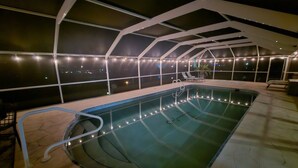 An indoor swimming pool with a glass ceiling, surrounded by a poolside area with chairs and a railing. - Heated Pool, Canal Front, Kayaks - Paradise Awaits!  (Port Charlotte)