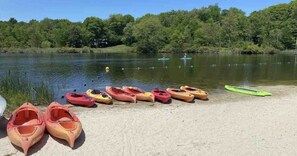 A lakeside view with several kayaks lined up on the shore.