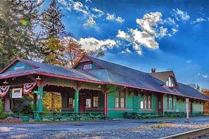 Una estación de tren histórica con zona de espera cubierta y mesas de picnic.