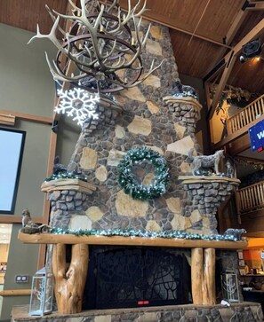 Una chimenea de piedra con repisa de madera, decorada con un adorno de guirnalda y cuernos de ciervo.