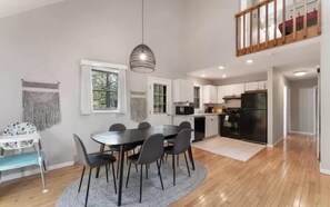 Una cocina moderna con comedor, suelo de madera y vistas al exterior.