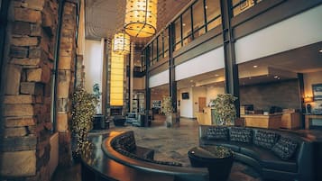 A spacious lobby with a curved seating area, a reception desk, and a large open space with high ceilings and modern lighting fixtures.