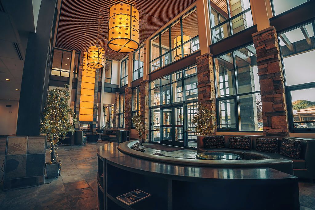 A spacious lobby with a reception desk, large windows, and a modern chandelier.