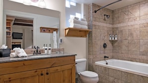 Un baño moderno con tocador de madera, inodoro, bañera y zona de ducha.