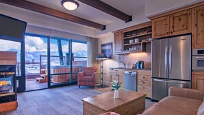 A modern kitchen with wooden cabinets, a stainless steel refrigerator, and a dining area with a wooden table and chairs.