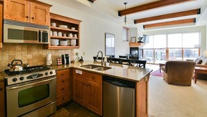 Una cocina con gabinetes de madera, un microondas de acero inoxidable, una estufa a gas y un lavavajillas.