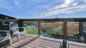 Un balcón con vista a un área cercada y montañas distantes.