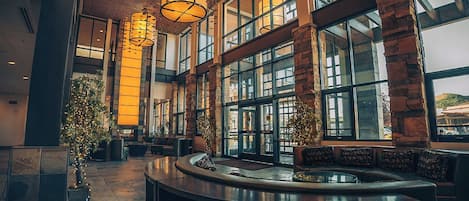 Un vestíbulo espacioso con mostrador de recepción, ventanas amplias y un moderno candelabro.
