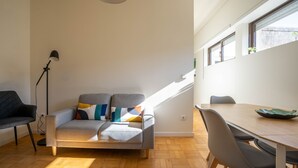 A modern living space with a sofa, a dining table, and a floor lamp. - Porto Heights by LovelyStay (Porto)