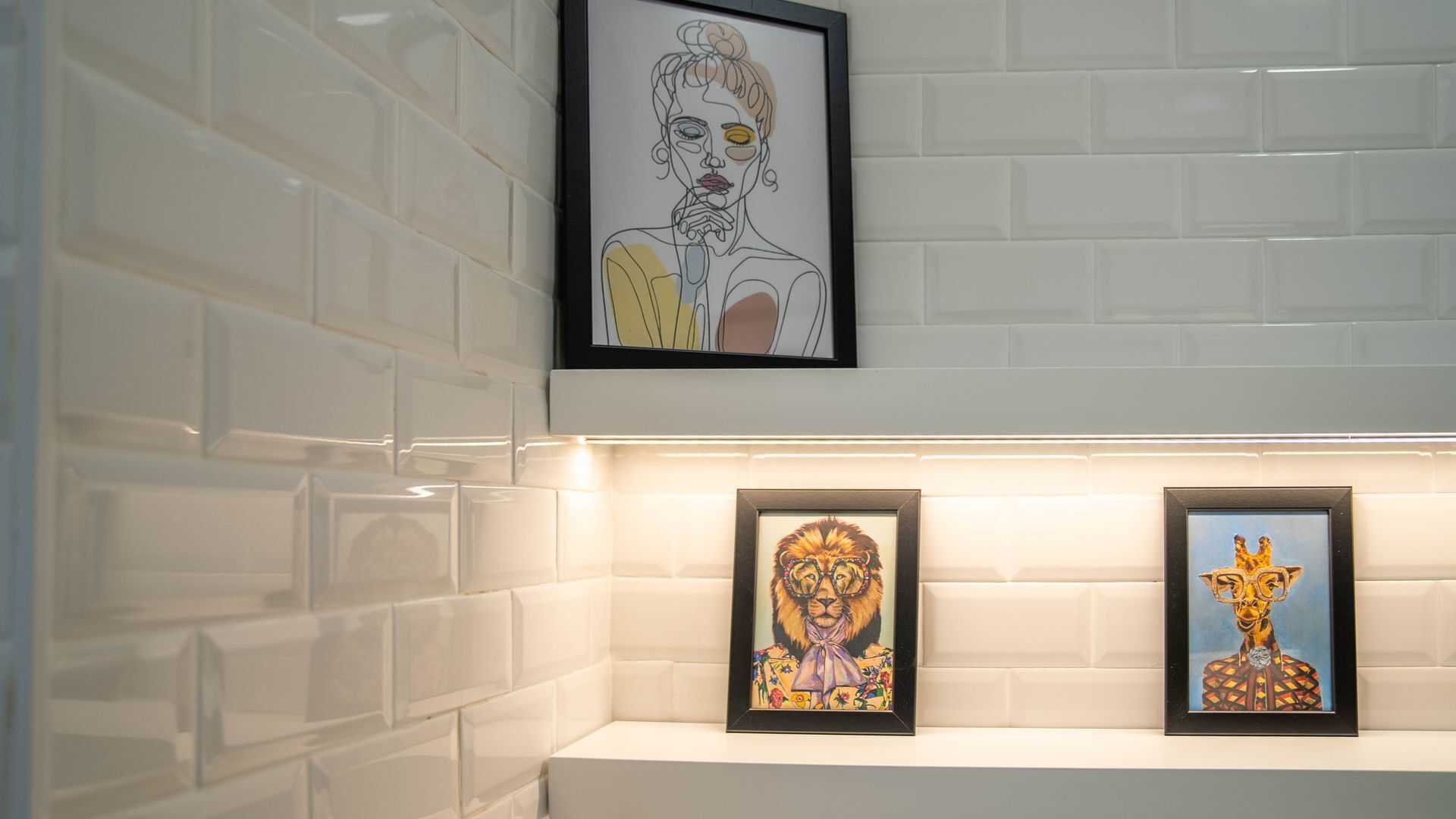 Een muur met drie ingelijste kunstwerken.