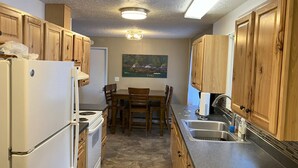Una cocina compacta con armarios de madera, un refrigerador, una estufa y una mesa de comedor con sillas.