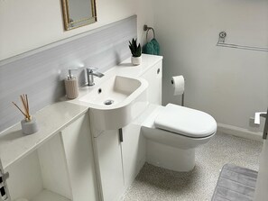 A modern bathroom with a white sink, a toilet, and a towel rack. - Captivating 2-bed Cottage in Kingsbarns (St. Andrews)