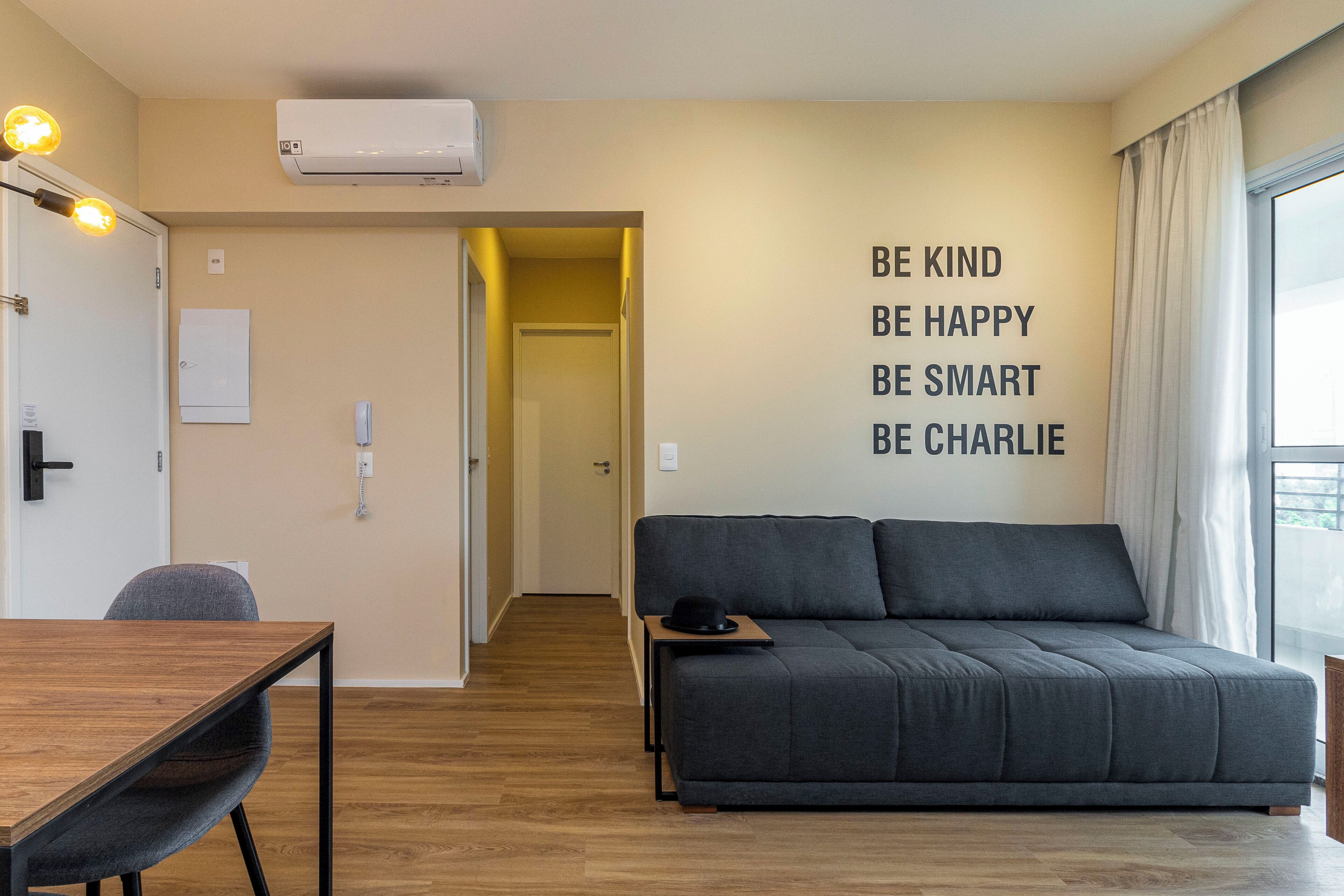 Una sala de estar moderna con un sofá, una mesa de madera y una pared con texto motivacional.