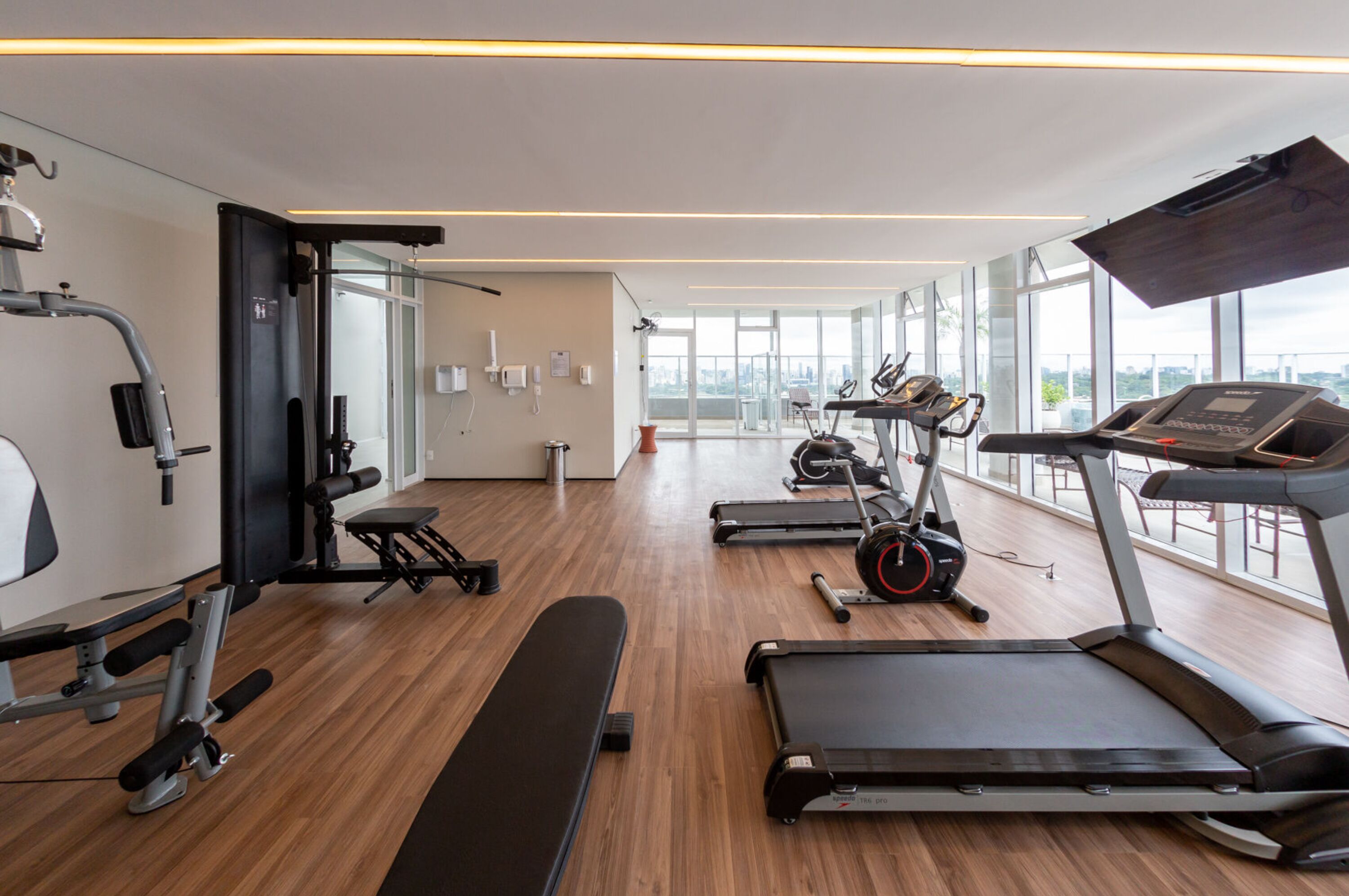 A modern gym with treadmills, elliptical machines, and weight benches.