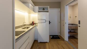 Una cocina compacta con refrigerador, microondas y cafetera.