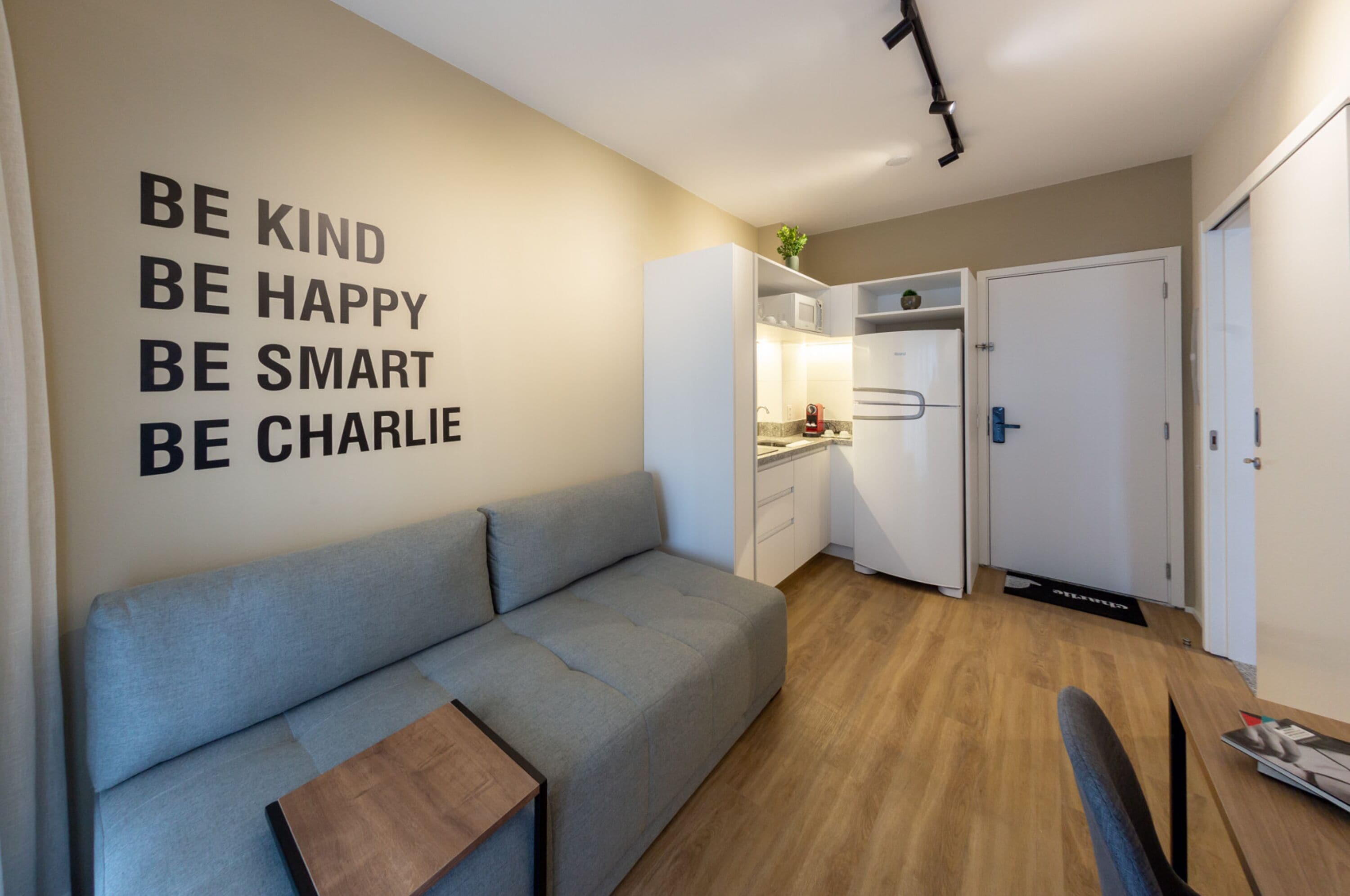 A modern living room with a grey sofa, a coffee table, and a wall with motivational quotes.