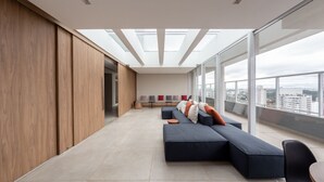 Una sala de estar moderna con un sofá seccional grande, un comedor y vistas de la ciudad a través de amplias ventanas.