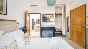 Une chambre d’hôtel avec un grand lit, une armoire en bois, un bureau avec une lampe et un tableau au mur.