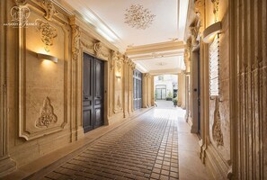 Un'imponente sala con elaborate decorazioni murali, pavimento in mattoni e un lampadario.