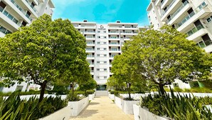 Um edifício de apartamentos moderno com um pátio central, paisagismo simétrico e céu claro.