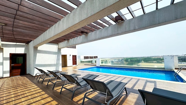 Uma área de piscina no terraço com espreguiçadeiras e vista para a cidade.