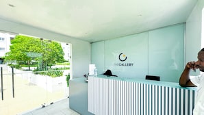 Bancada de recepção com logotipo, divisória de vidro e vista para o exterior com vegetação.