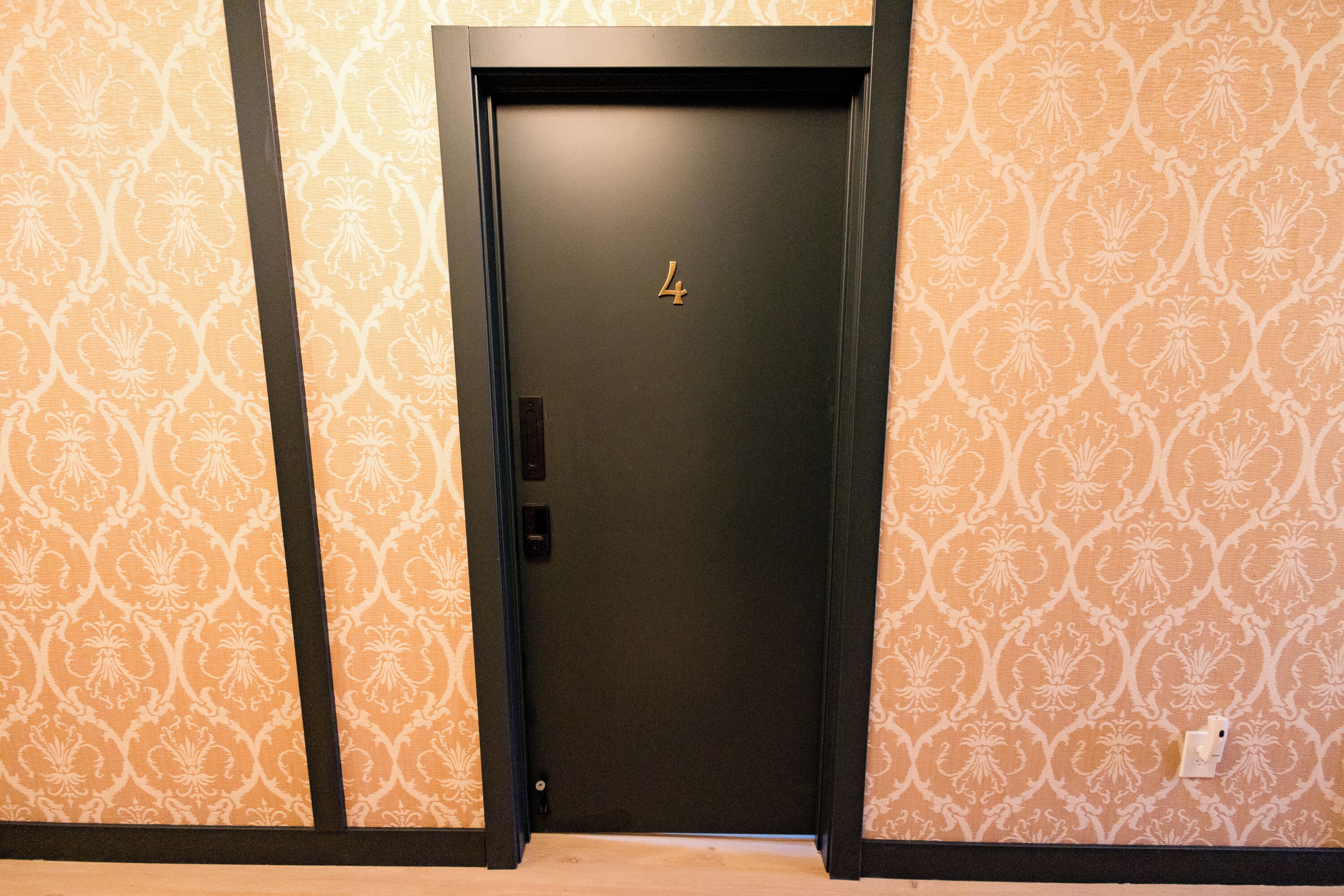 Una puerta con el número 4, ubicada en una habitación con papel tapiz estampado.
