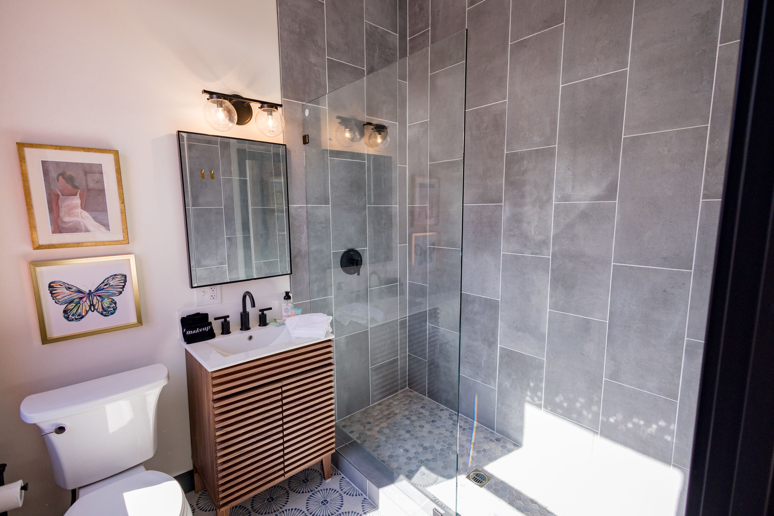 A modern bathroom with a toilet, vanity, sink, and shower.