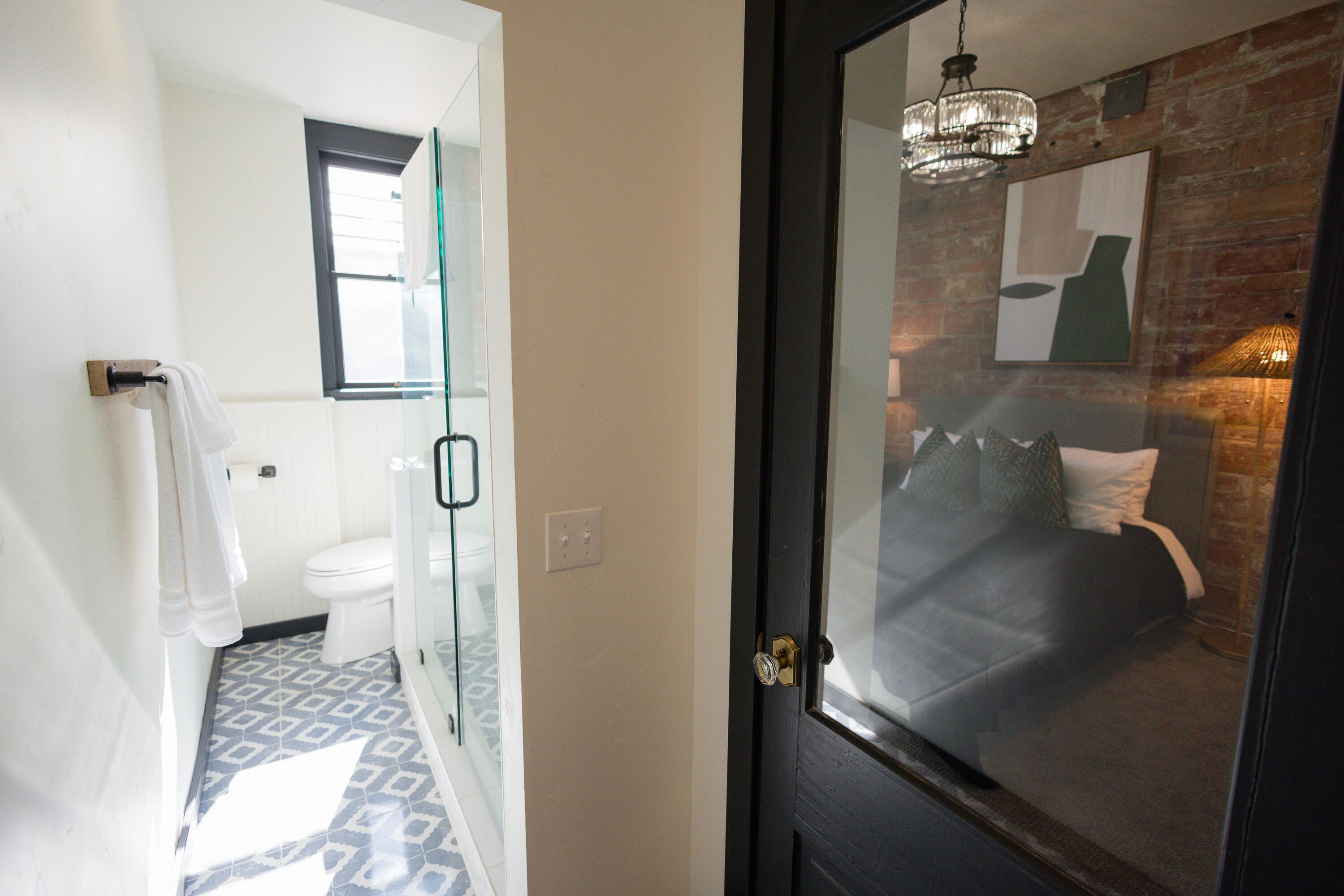 A bathroom with a patterned floor, a toilet, and a glass shower enclosure.
