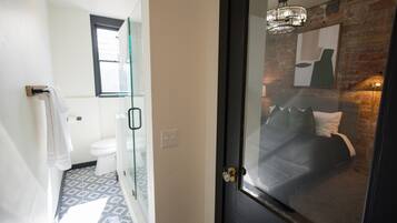 A bathroom with a patterned floor, a toilet, and a glass shower enclosure.