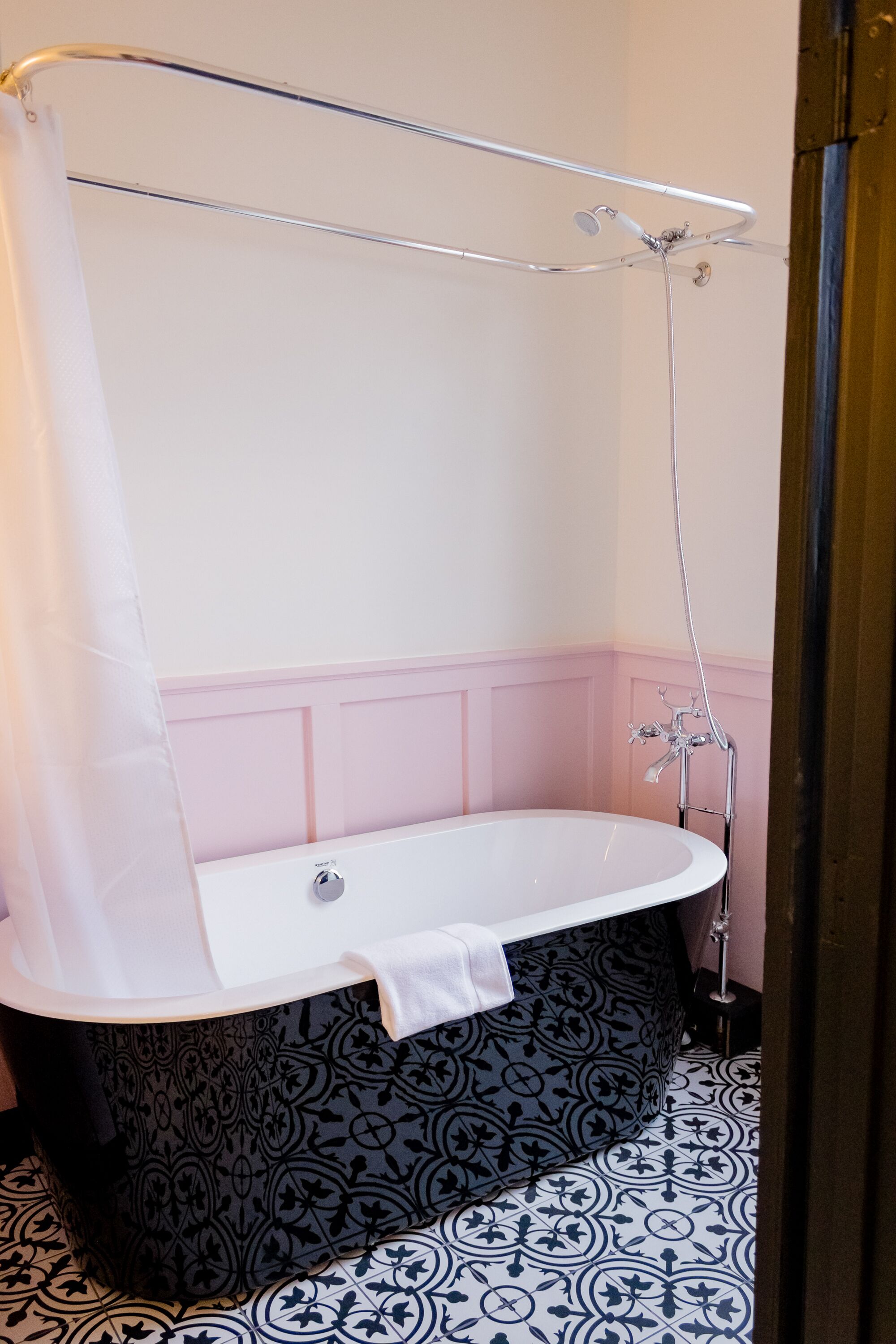 Een badkamer met een vrijstaand bad, een douche en een vloer met een patroon.