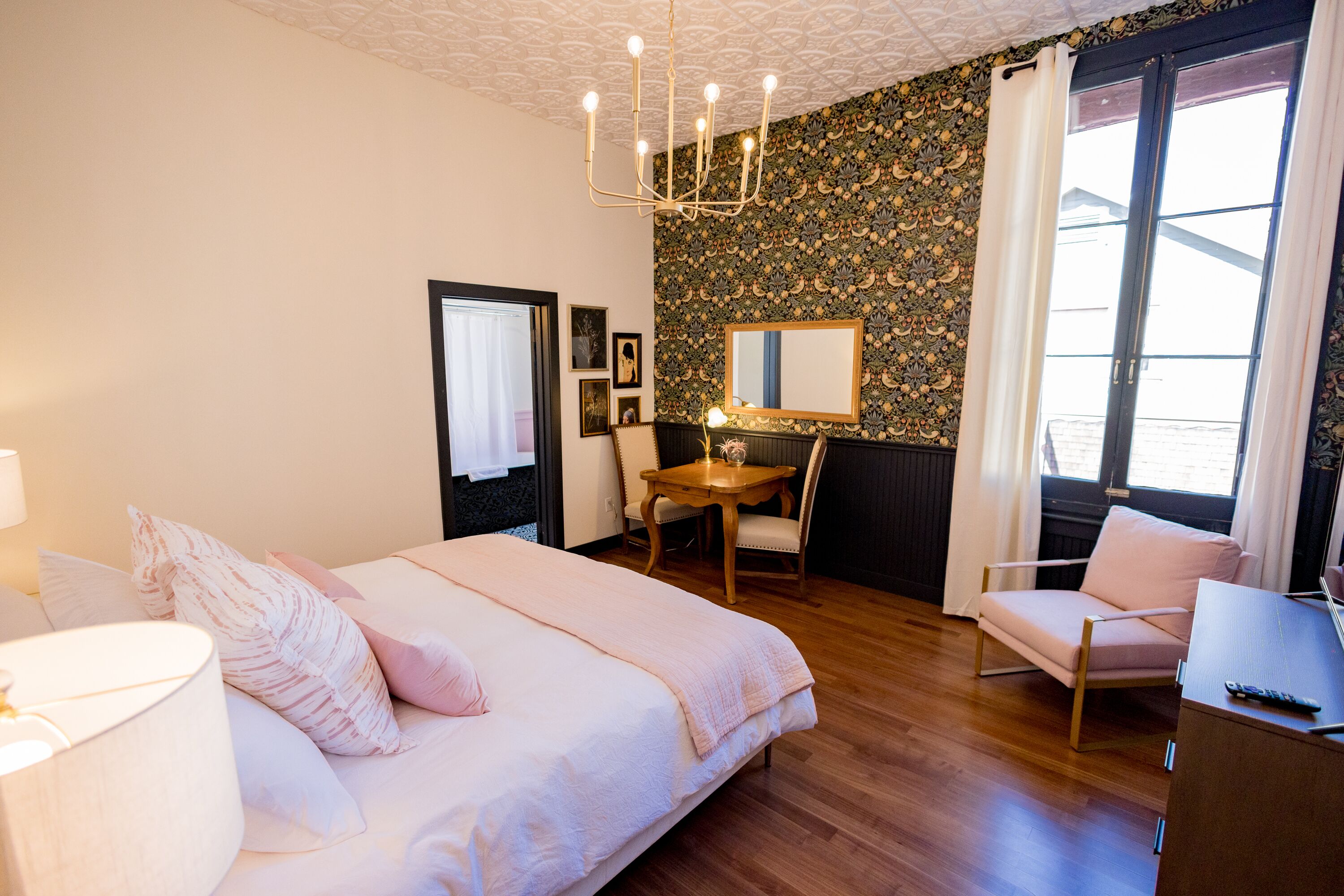 Un dormitorio con una cama, un escritorio, una silla y un ventanal grande.