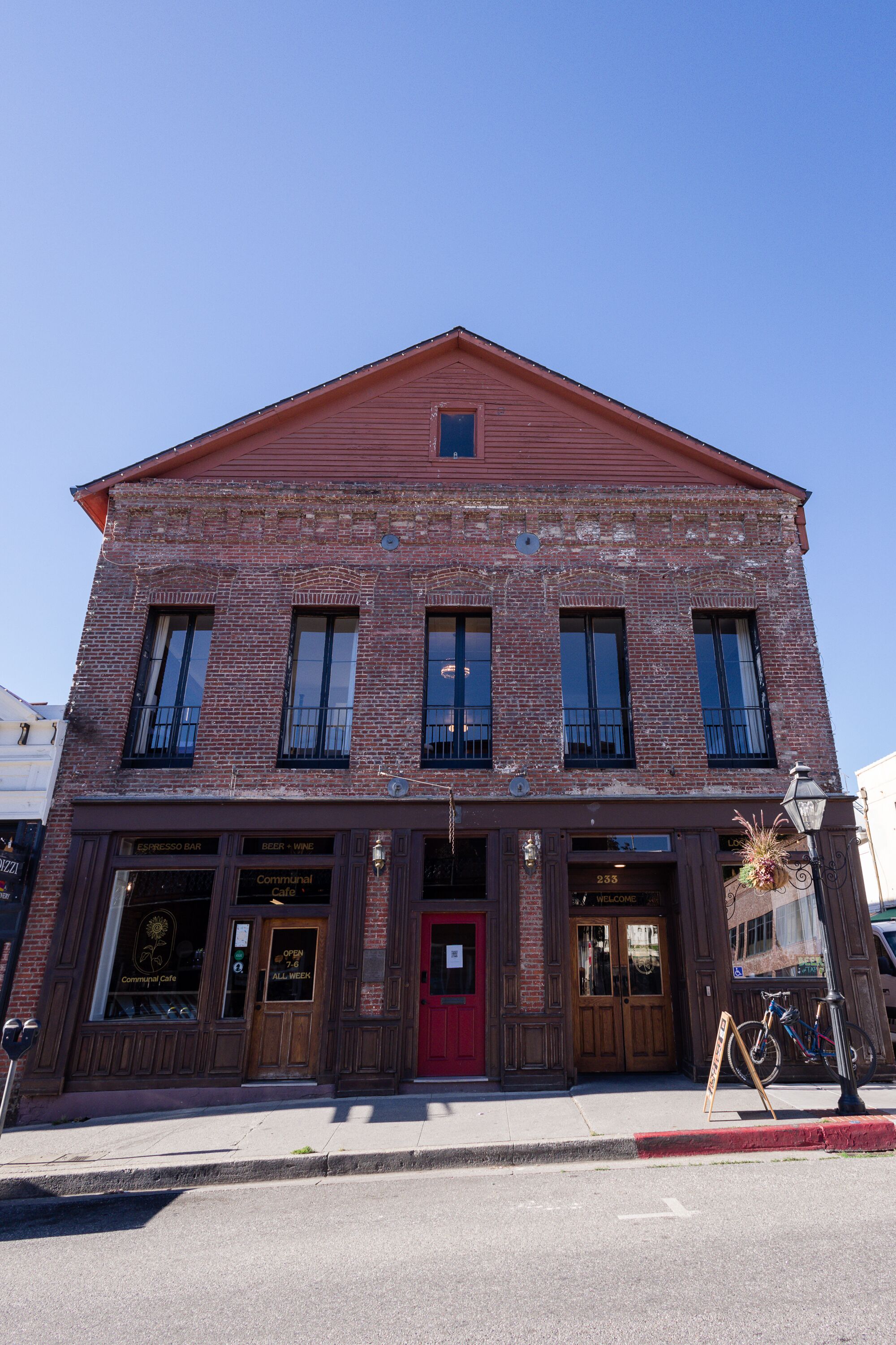 A two-story brick building with a red door and windows.