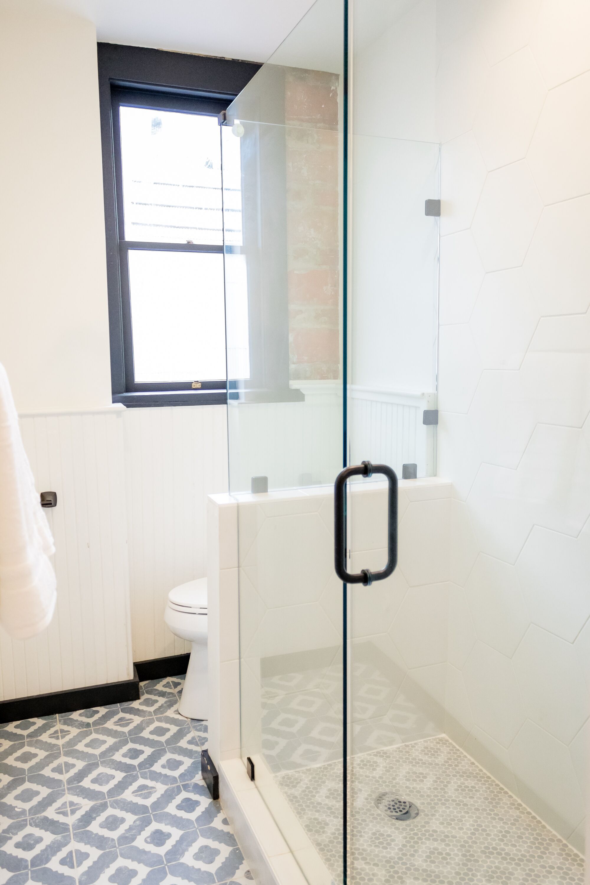 Un baño con ducha de vidrio, inodoro y ventana.