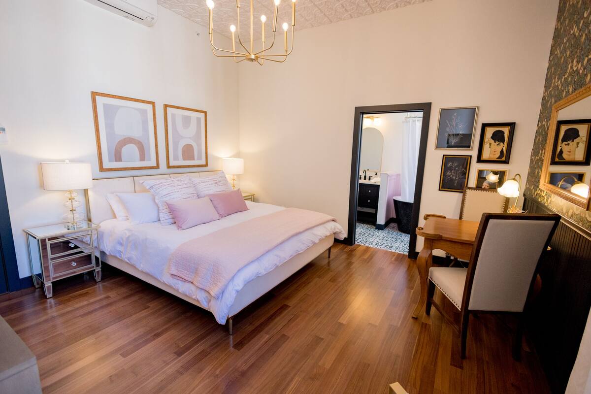 Quarto com cama, mesa de cabeceira, abajur e espelho.