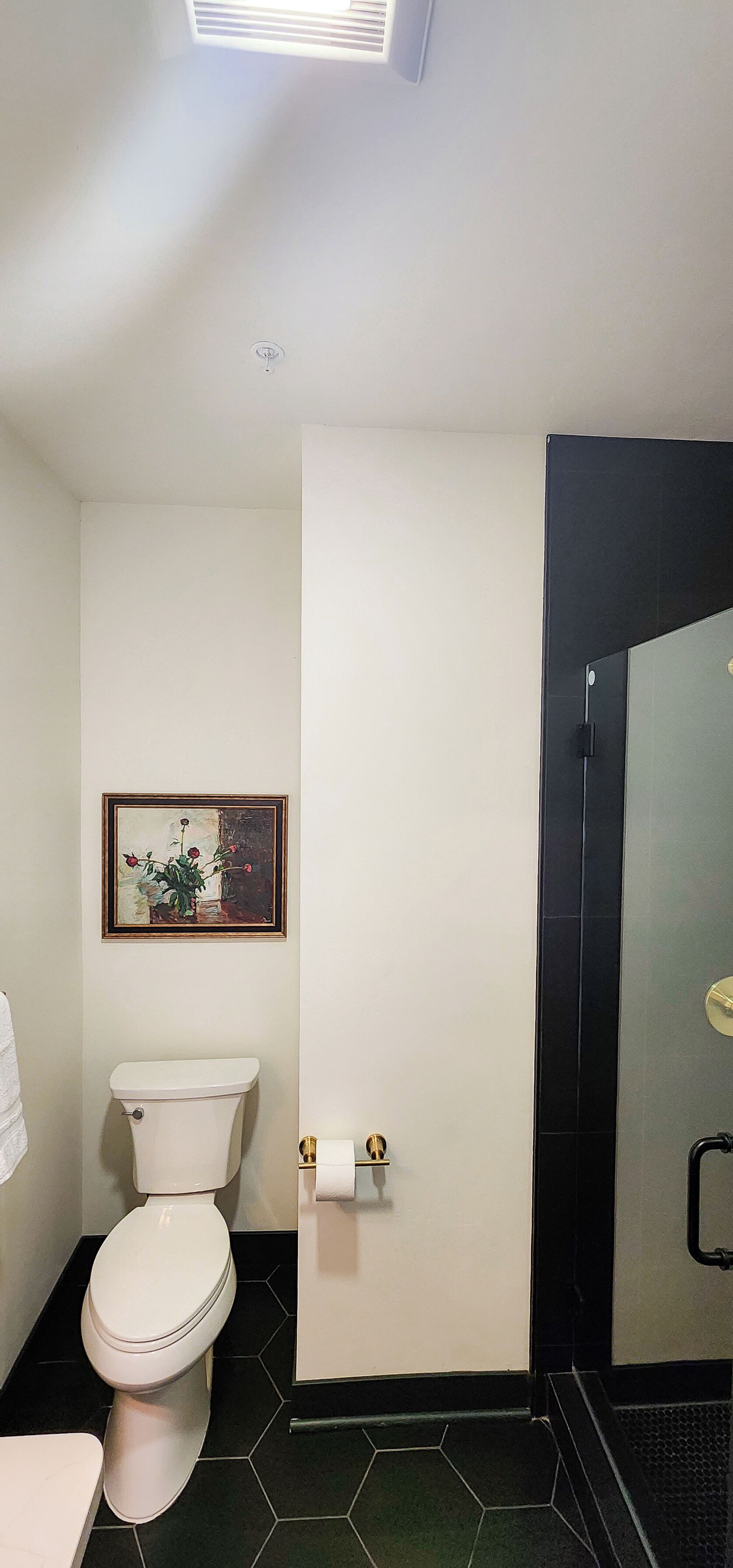 Ein Badezimmer mit Toilette, einem gerahmten Bild an der Wand und einer Duschkabine.