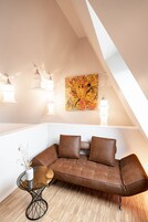 Un espacio tipo loft con un sofá de cuero marrón, una mesa de centro de vidrio y un cuadro en la pared.