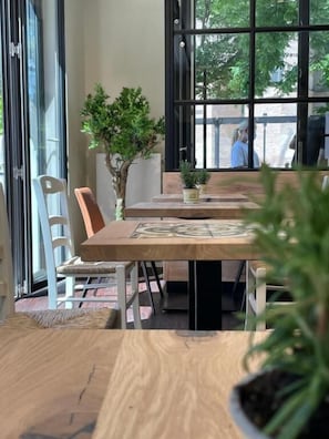 Un interior modern amb una taula de fusta, cadires i una finestra gran que dona a l'exterior.